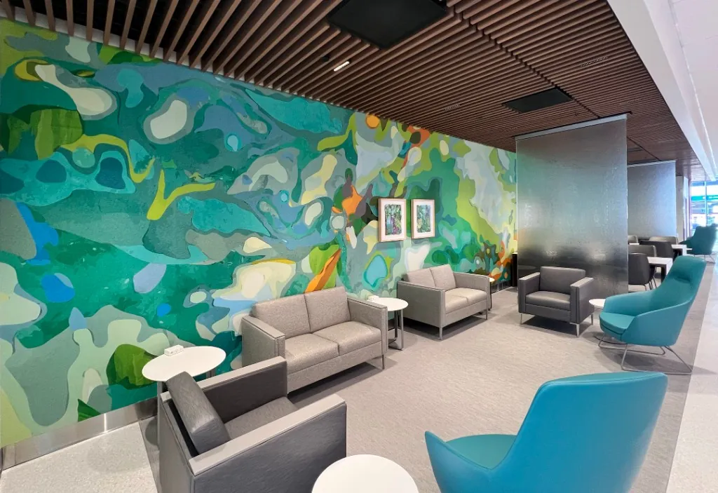 Sweeping blue-and-green abstract mural filling a UC San Diego Health lounge.