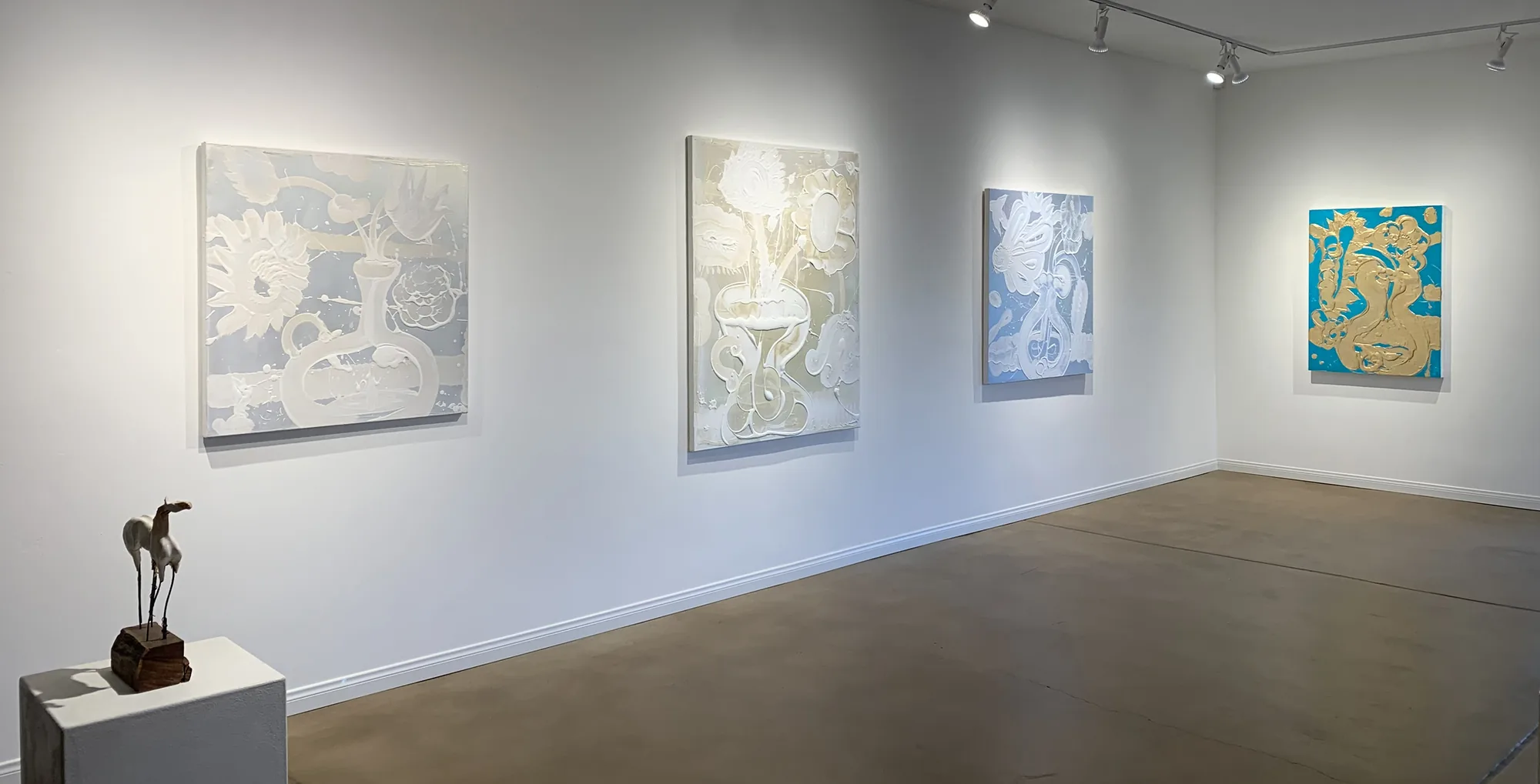 The Susan Street Fine Art gallery interior, paintings on white walls with a sculpture on a pedestal.